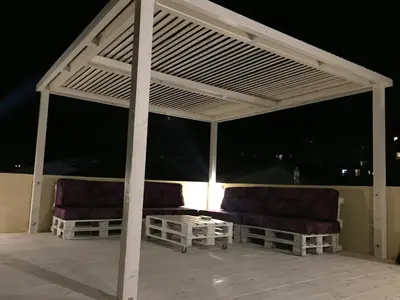 a pergola with two chairs on a patio at night at Soheds in Budva