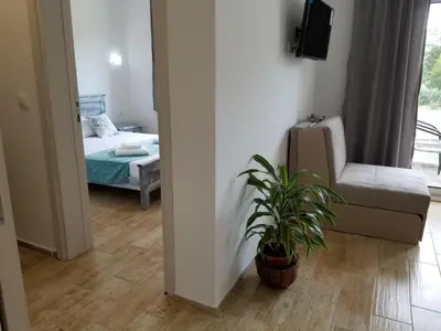 a bedroom with a bed and a chair and a plant at Riviera Inn apartments in Ulcinj