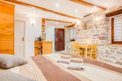 a bedroom with a large bed and a stone wall at Kotor Bagus - Cozy Boutique Old Town Studio with Seaview Terrace in Kotor
