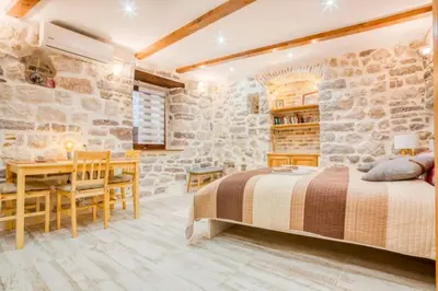 a bedroom with a bed and a table and a desk at Kotor Bagus - Cozy Boutique Old Town Studio with Seaview Terrace in Kotor