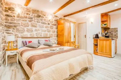 a bedroom with a large bed and a stone wall at Kotor Bagus - Cozy Boutique Old Town Studio with Seaview Terrace in Kotor