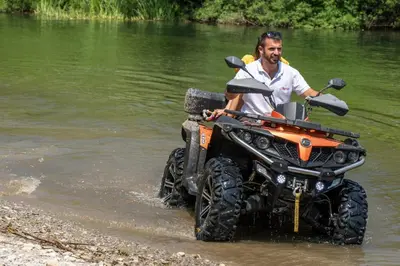 a man is sitting on an atv in the water at Wooden Village Resort in Ponari