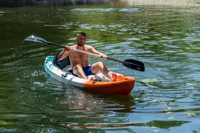 a man in an orange kayak in the water at Wooden Village Resort in Ponari