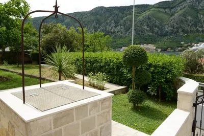 a hot tub in a garden with mountains in the background at Apartmani Ćetković in Kotor