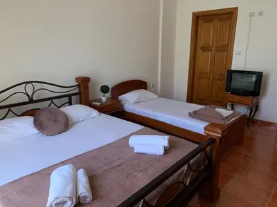 two beds in a room with a tv and a room with towels at Guesthouse Orlović in Budva