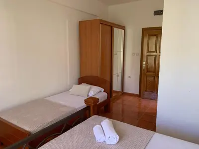 a room with two beds and a closet and a door at Guesthouse Orlović in Budva