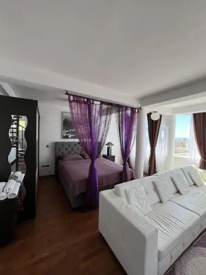 a bedroom with a white couch and a purple bed at Accommodation Royal Azur in Dobra Voda