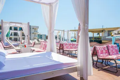 a bed on a patio with chairs and tables at Accommodation Royal Azur in Dobra Voda