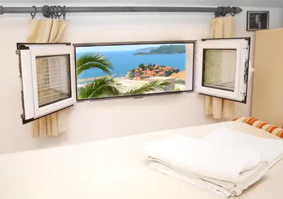 a bedroom with two windows with a view of the ocean at Apartments Antonela in Sveti Stefan