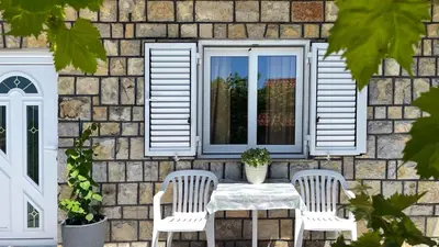 a patio with a table and two chairs and a window at Apartments Antonela in Sveti Stefan