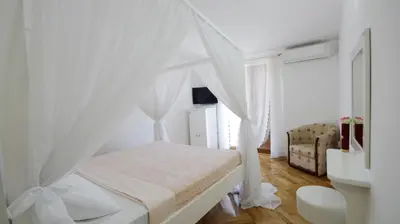 a white bedroom with a bed with a canopy at Apartments Miković in Budva