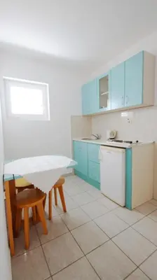 a kitchen with blue cabinets and a table and chairs at Apartments Miković in Budva