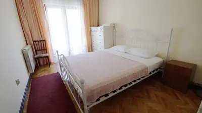 a bedroom with a white bed with a dresser and a window at Apartments Miković in Budva