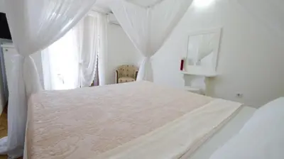 a white bedroom with a white bed with a window at Apartments Miković in Budva