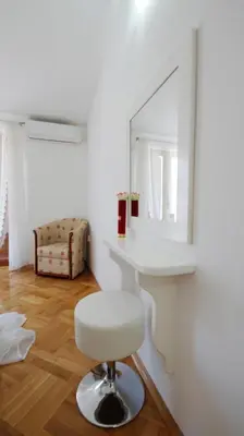 a white room with a stool and a mirror at Apartments Miković in Budva