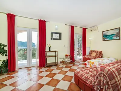 a bedroom with red curtains and a bed and a couch at Apartments Midžor in Petrovac na Moru