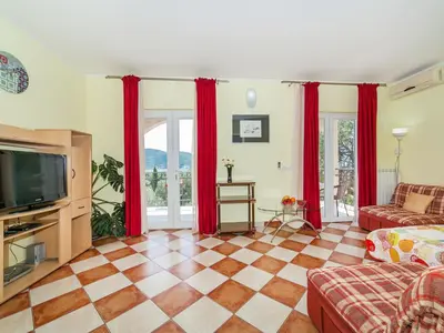 a living room with red curtains and a television at Apartments Midžor in Petrovac na Moru