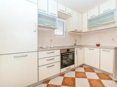 a kitchen with white cabinets and a checkered floor at Apartments Midžor in Petrovac na Moru