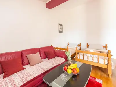 a living room with a red couch with a bowl of fruit at Apartments Midžor in Petrovac na Moru