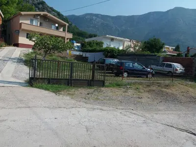 a fence in front of a house with cars parked at Apartmani Joca in Sutomore