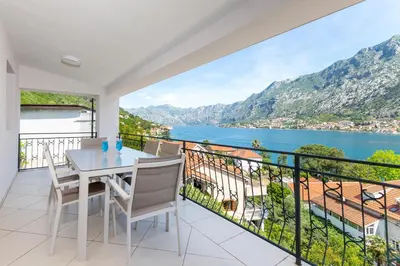 a balcony with a table and chairs and a view of the water at Apartments Dončić in Kotor