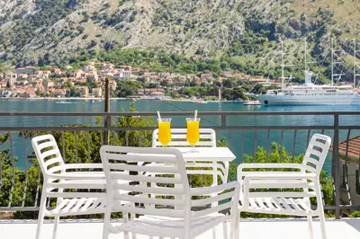 a table with two glasses of orange juice on a balcony at Apartments Dončić in Kotor