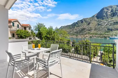 a balcony with a table and chairs and a view of the water at Apartments Dončić in Kotor