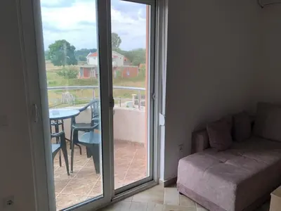 a living room with a couch and a balcony with a table at S T A Apartmani in Ulcinj