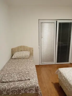 a bedroom with two beds and a window with blinds at Malina apartman in Utjeha