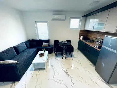 a living room with a blue couch and a kitchen at Malina apartman in Utjeha