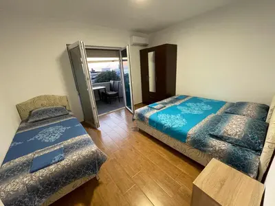 a room with two beds and a balcony with a table at Malina apartman in Utjeha