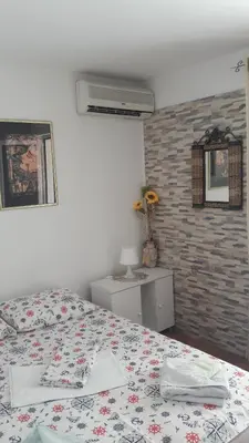a bedroom with a bed and a brick wall at Apartmani Dačo in Sveti Stefan