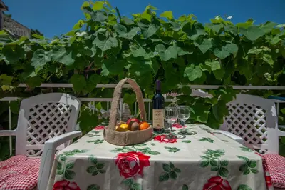 a table with a basket of fruit and a bottle of wine at Apartmani Dačo in Sveti Stefan