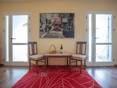 a dining room table with two chairs and a red rug at Apartmani Dačo in Sveti Stefan