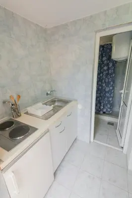 a white kitchen with a sink and a shower at Rooms Molabeciri in Ulcinj