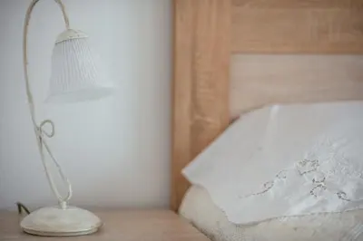 a white lamp sitting on a table next to a bed at Big Hill Apartment in Kotor