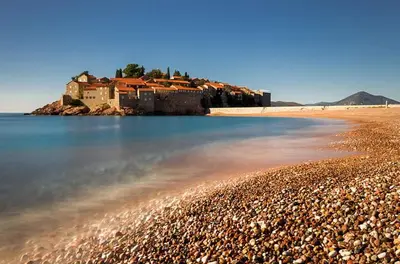 a beach with a house on top of a hill at Apartment M&M in Sveti Stefan