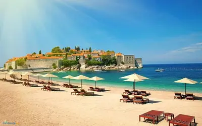 a beach with tables and chairs and umbrellas at Apartment M&M in Sveti Stefan