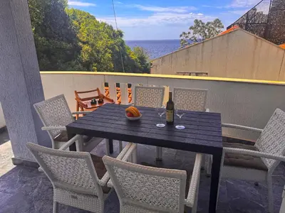 a table with chairs and a bottle of wine on a balcony at Apartment M&M in Sveti Stefan