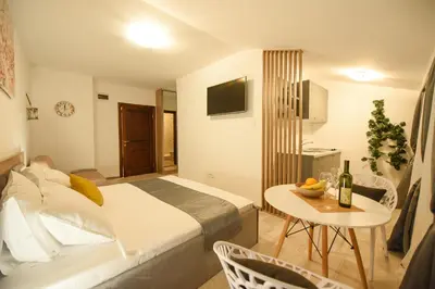 a hotel room with a bed and a table with a bottle of wine at Korzo apartmani in Podgorica