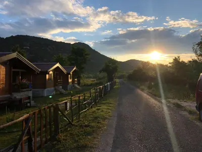 a road with a house and the sunset in the background at Orahovo Cottages in Virpazar