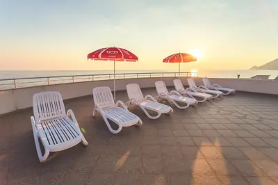 a row of white chairs and umbrellas on a pier at Apartments Deus in Dobra Voda