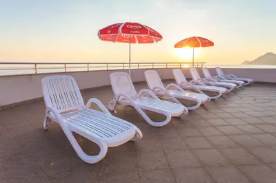 a row of white chairs and umbrellas on a roof at Apartments Deus in Dobra Voda