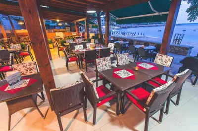 a restaurant with tables and chairs and a view of the water at Apartments Deus in Dobra Voda