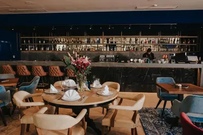 a dining room with tables and chairs and a bar at Ramada by Wyndham Podgorica in Podgorica