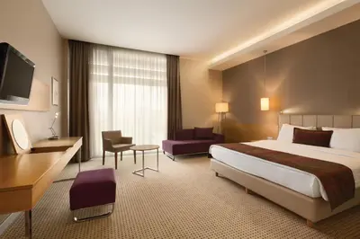 a hotel room with a bed and a desk and chair at Ramada by Wyndham Podgorica in Podgorica