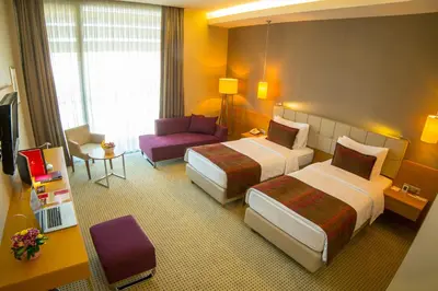 a hotel room with two beds and a chair at Ramada by Wyndham Podgorica in Podgorica