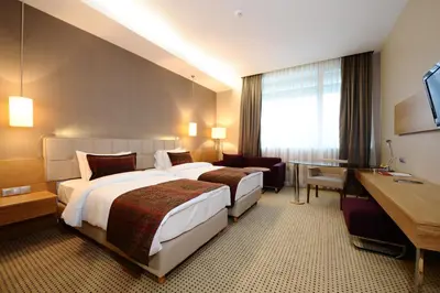 a hotel room with two beds and a desk at Ramada by Wyndham Podgorica in Podgorica