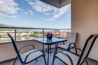 a table with chairs and a vase of flowers on a balcony at Adriatik Lux Apartments in Budva