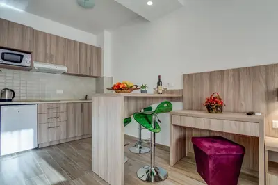 a kitchen with wooden cabinets and a green stool at Adriatik Lux Apartments in Budva